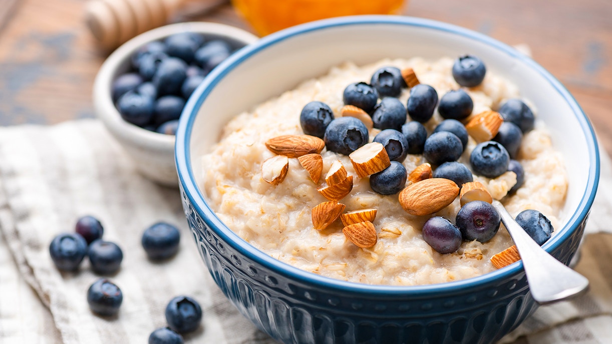 Oatmeal topped with fresh blueberries and almonds in a blue bowl.