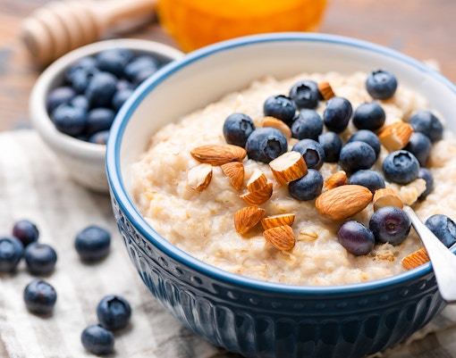 Oatmeal topped with fresh blueberries and almonds in a blue bowl.