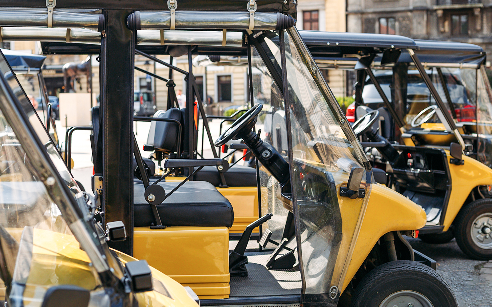 Electric open cars parked in a row on a city street.