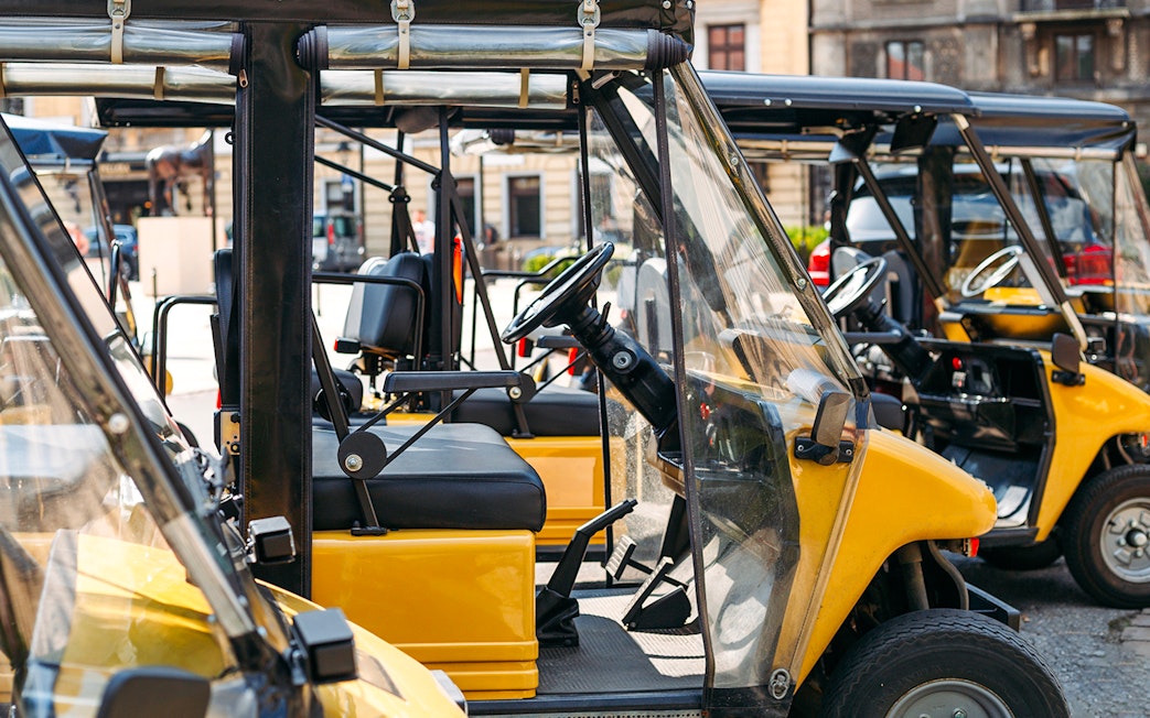 Electric open cars parked in a row on a city street.