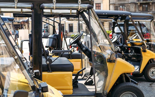 Electric open cars parked in a row on a city street.