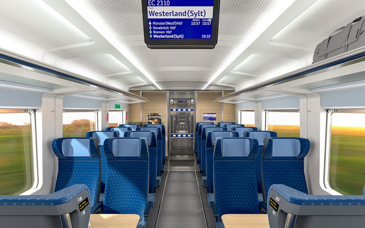 Interior of an Intercity train on the Eurail route in Germany, showing blue seats and overhead luggage space.
