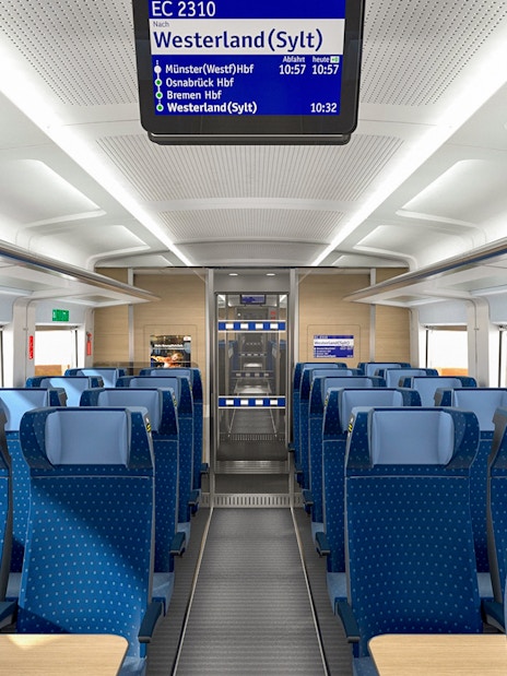 Interior of an Intercity train on the Eurail route in Germany, showing blue seats and overhead luggage space.
