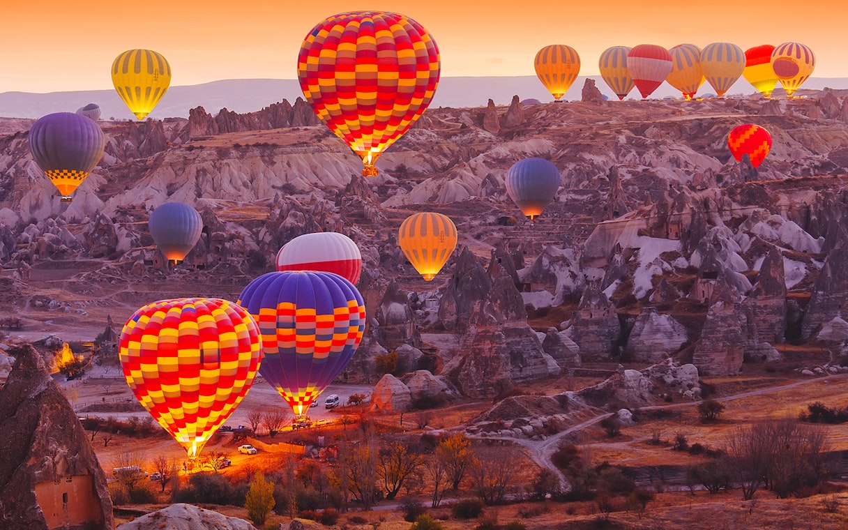 Hot air balloons over Cappadocia landscape at sunrise, showcasing safety measures in place.
