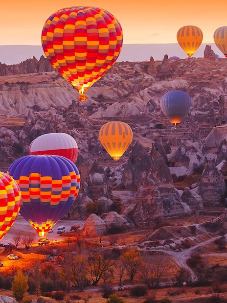 Hot air balloons over Cappadocia landscape at sunrise, showcasing safety measures in place.