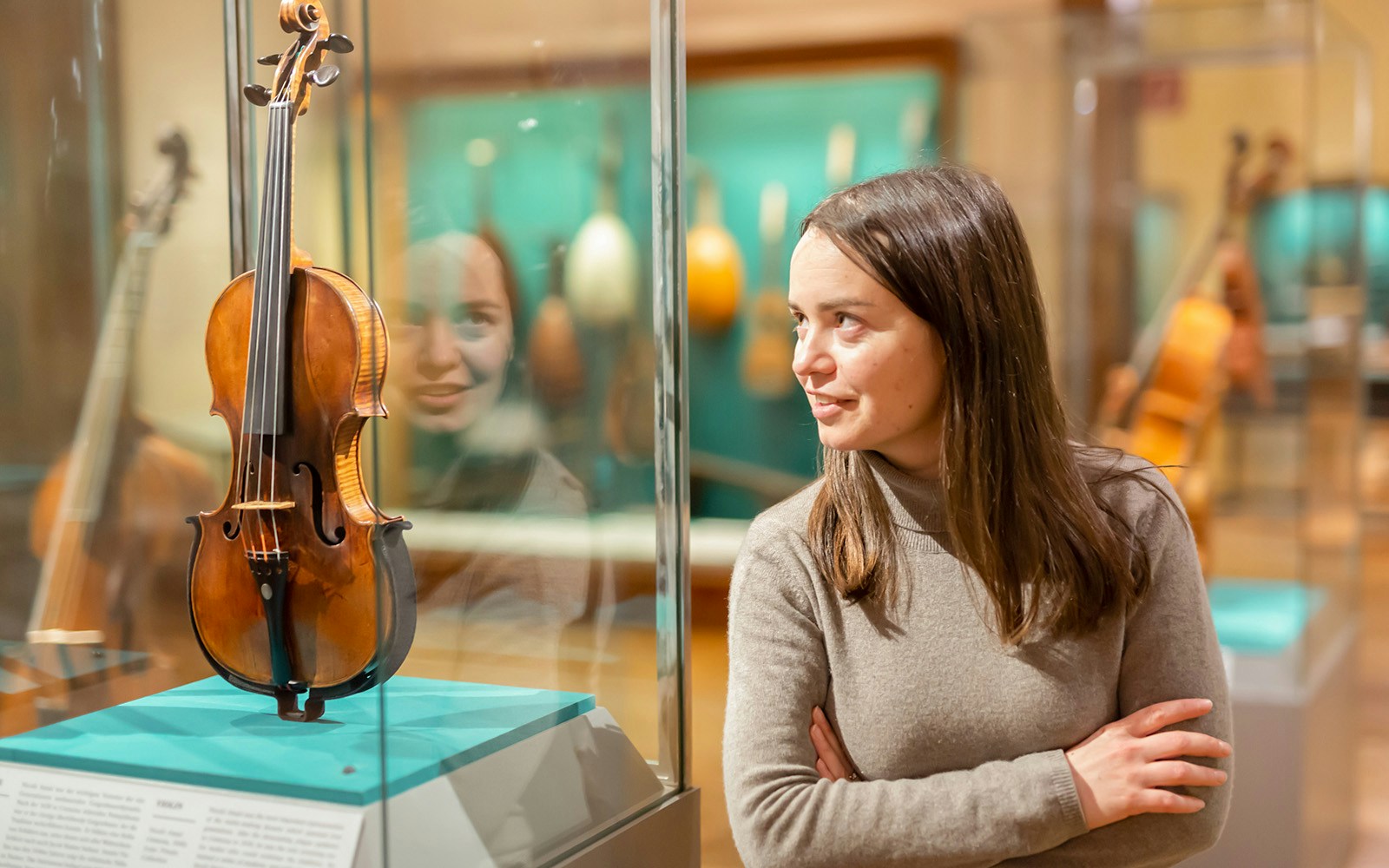 Portrait of interested adult brunette visiting exhibition of medieval musical instruments in historical museum