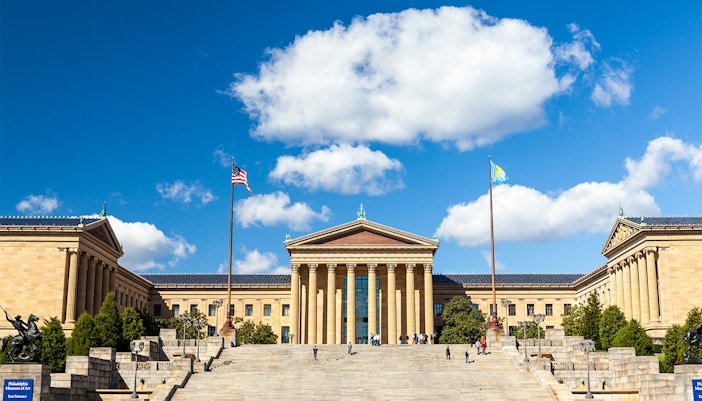 Philadelphia Museum of Art facade with steps and flags under a blue sky.