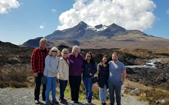 Group of tourists on Isle of Skye day trip with mountains in background, Inverness.
