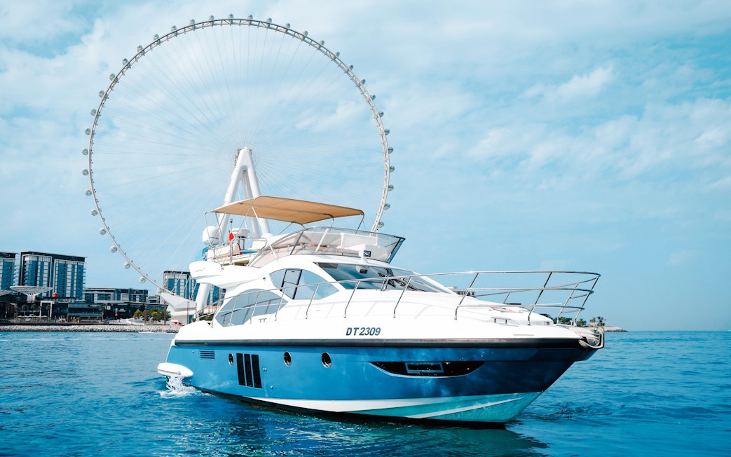 Private luxury yacht sailing near Ain Dubai Ferris wheel.