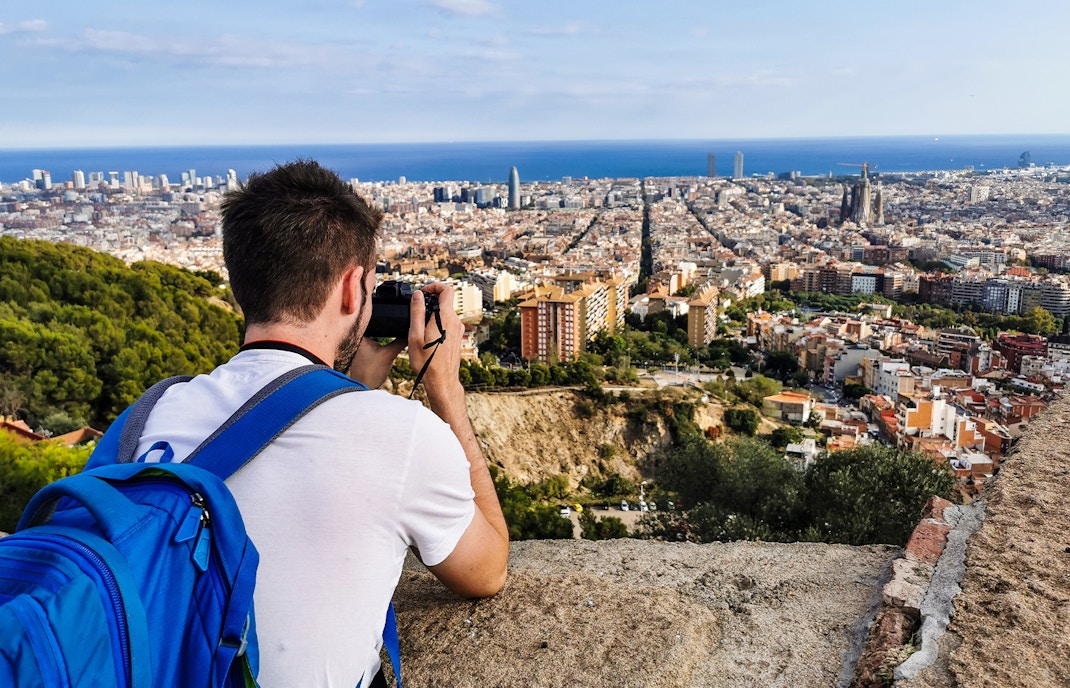 Person photographing Barcelona skyline from Bunkers del Carmel viewpoint.