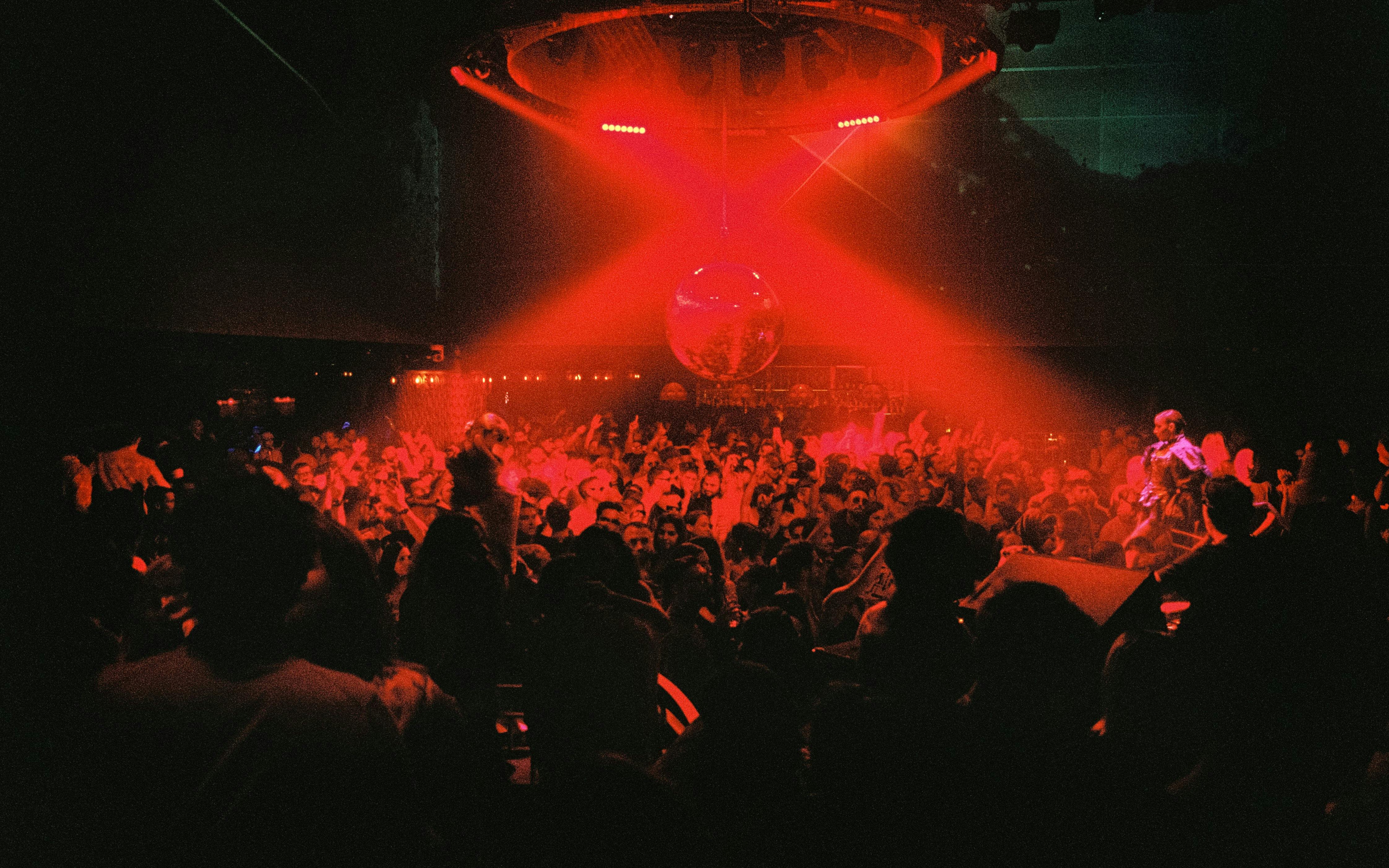 DJ performing at La Troya Club Chinois, Ibiza with vibrant crowd and red lighting.