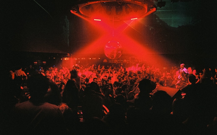 DJ performing at La Troya Club Chinois, Ibiza with vibrant crowd and red lighting.