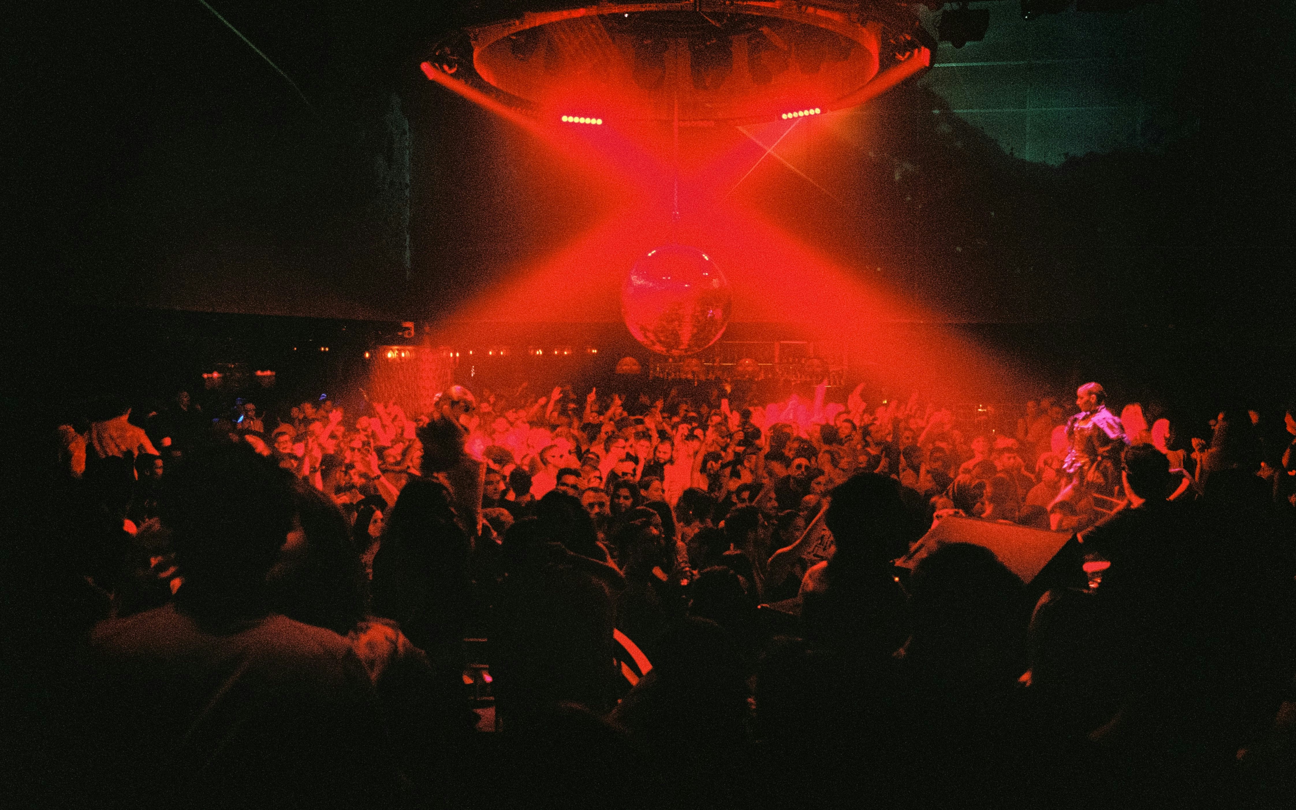 DJ performing at La Troya Club Chinois, Ibiza with vibrant crowd and red lighting.