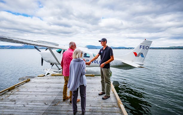 Floatplane tour guide greeting tourists on dock in Rotorua for Mt Tarawera and Waimangu Thermal Valley tour.