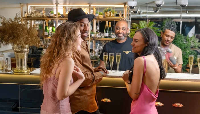 Three people cheering with their drinks in the Champagne Bar inside Madame Tussauds of London