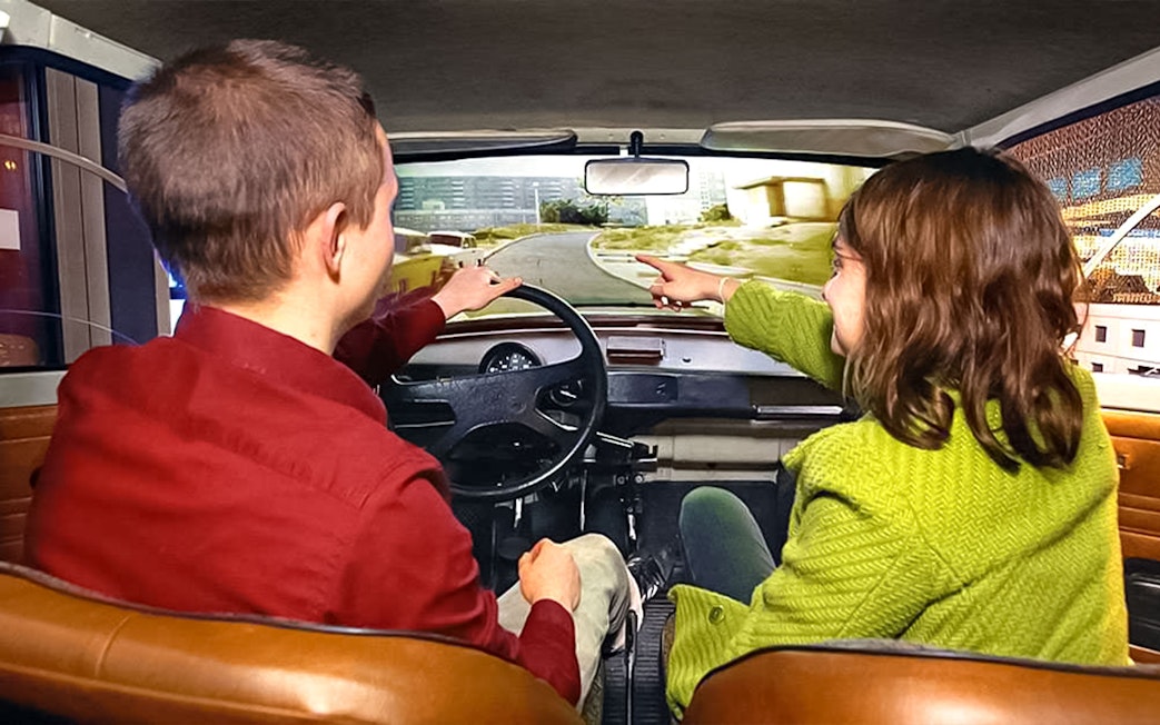 Visitors in a simulated car experience at DDR Museum Berlin.