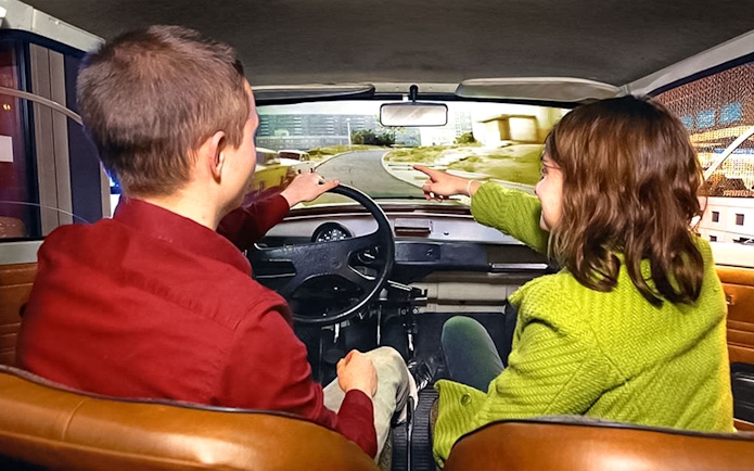 Visitors in a simulated car experience at DDR Museum Berlin.