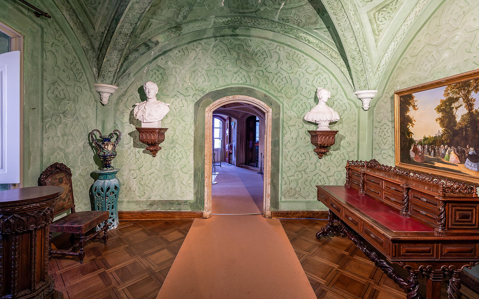 Interior of National Palace of Pena with ornate green walls, sculptures, and antique furniture.