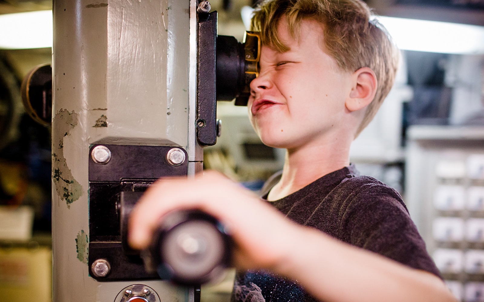 Child looking through a periscope at a San Diego museum exhibit.