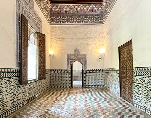 Corridor view inside Alcazar Seville showcasing intricate arches and detailed Moorish architecture.