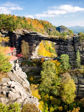 Pravčická Brána rock formation in Bohemian Switzerland with surrounding autumn foliage.