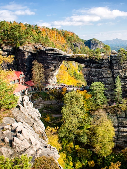 Pravčická Brána rock formation in Bohemian Switzerland with surrounding autumn foliage.