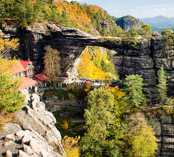 Pravčická Brána rock formation in Bohemian Switzerland with surrounding autumn foliage.