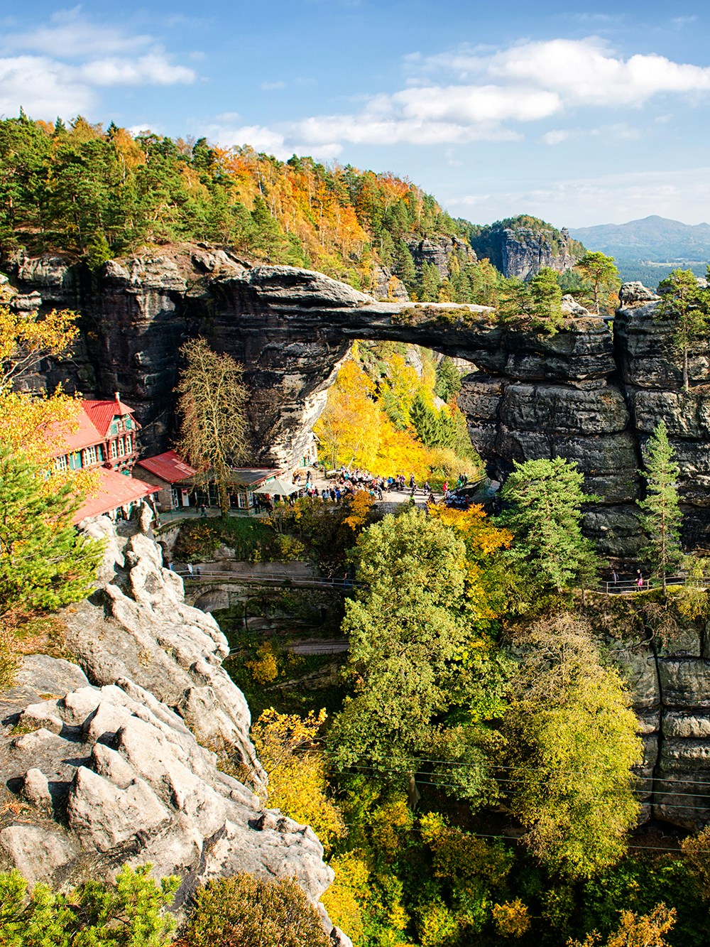Pravčická Brána rock formation in Bohemian Switzerland with surrounding autumn foliage.
