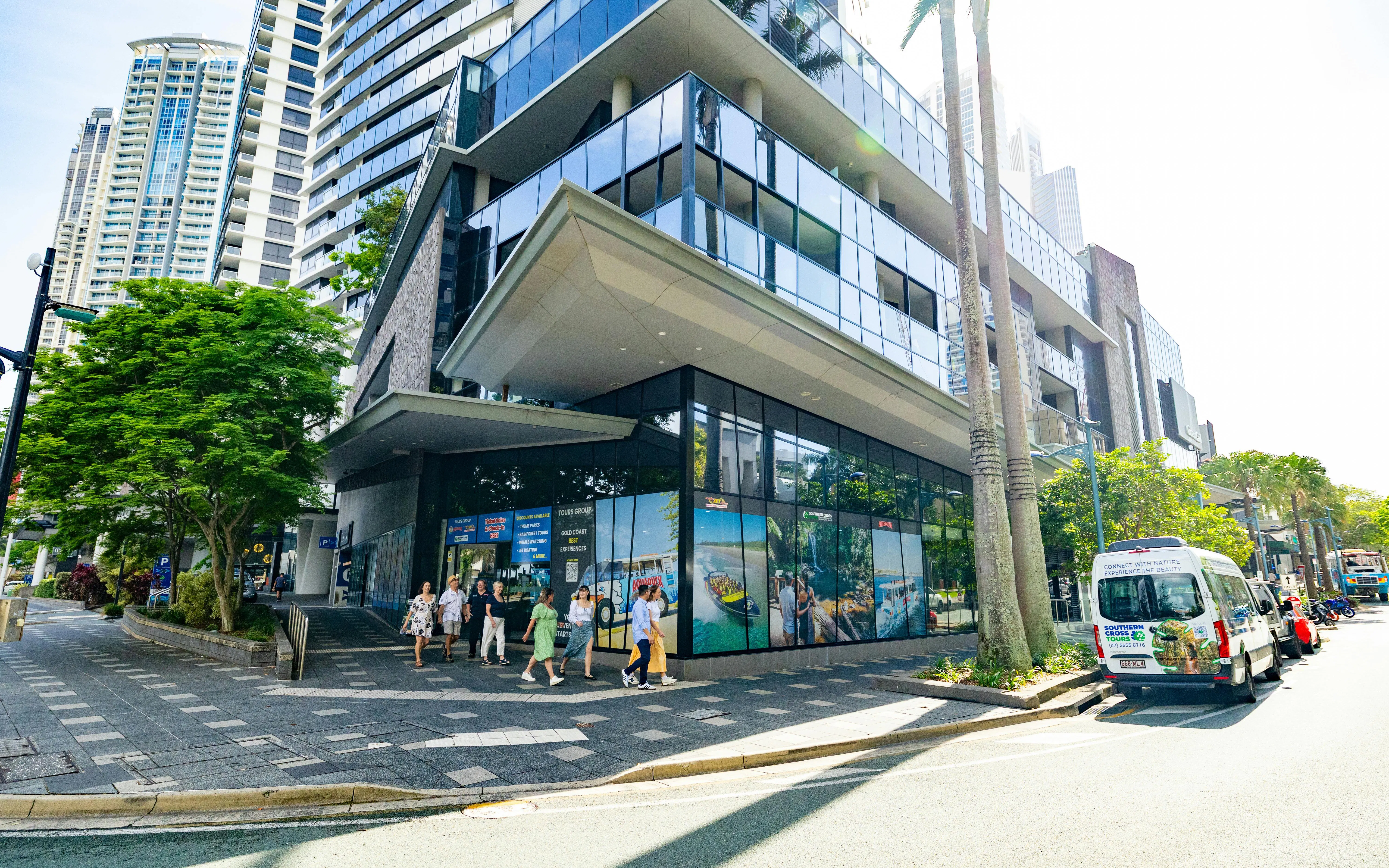 Tourists walking near a modern building with tour advertisements in Tamborine Mountain.