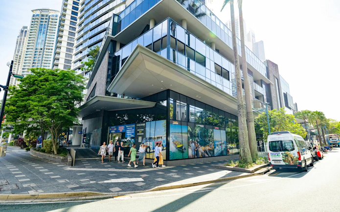 Tourists walking near a modern building with tour advertisements in Tamborine Mountain.