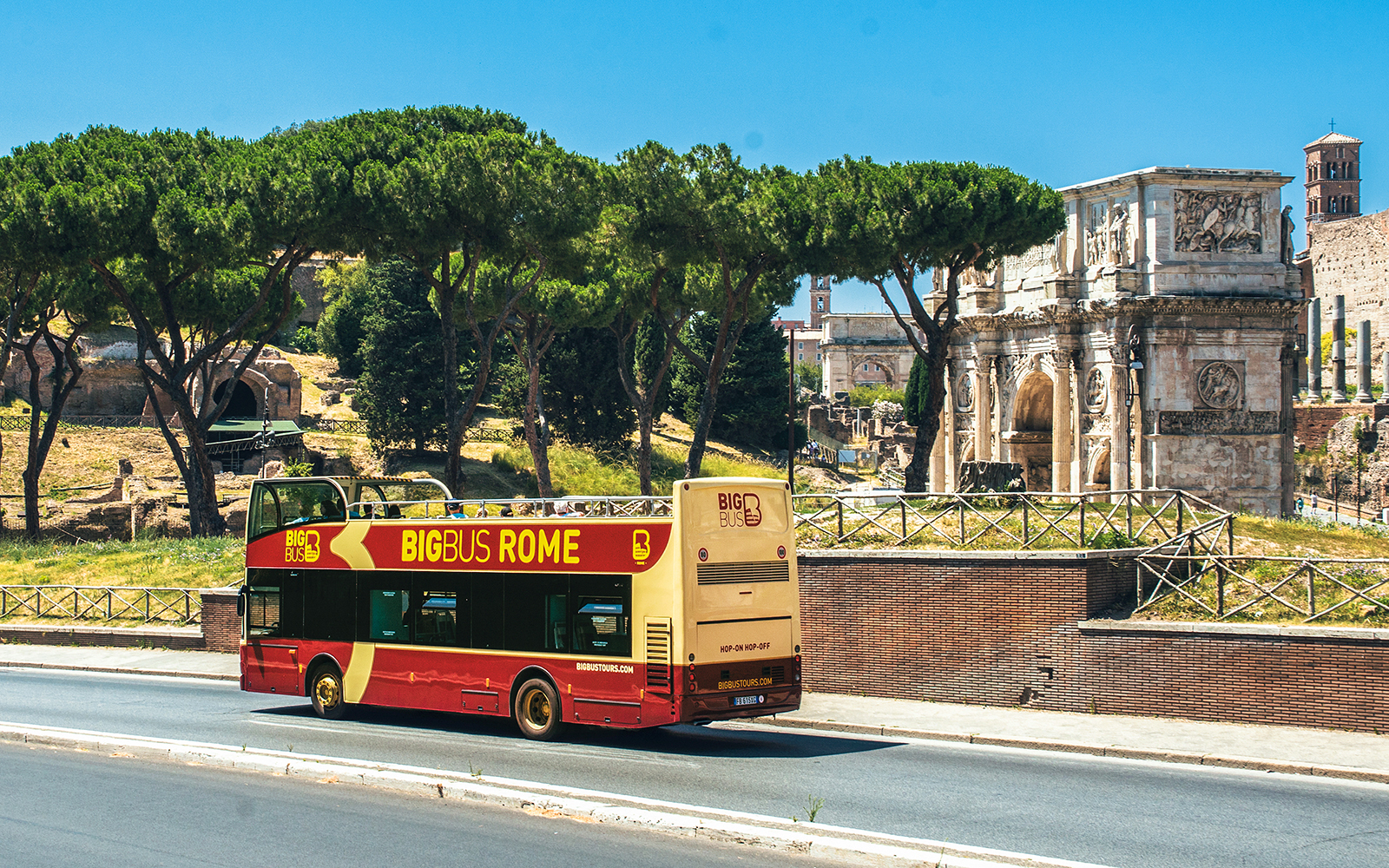 Big Bus Rome tour passing by the Arch of Constantine with tourists on board.