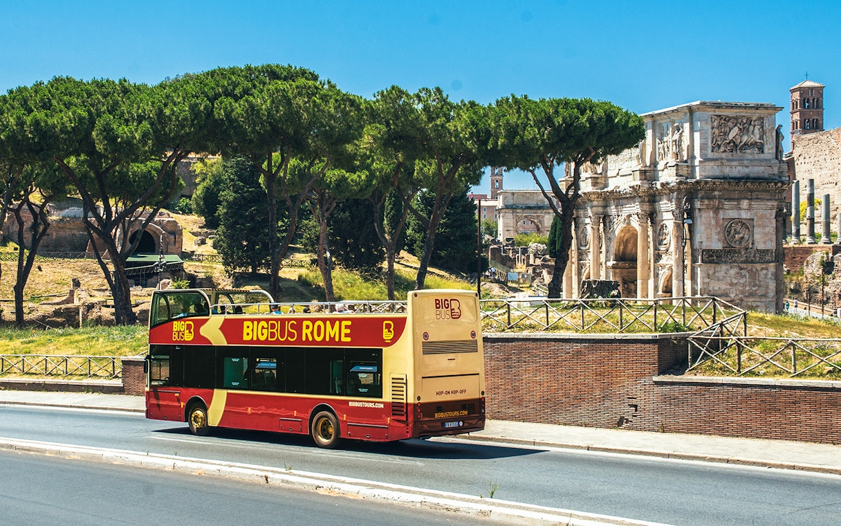 Big Bus Rome tour passing by the Arch of Constantine with tourists on board.