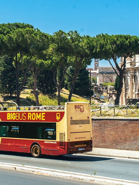 Big Bus Rome tour passing by the Arch of Constantine with tourists on board.