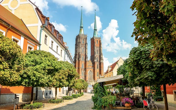 Wroclaw Cathedral with surrounding colorful buildings and trees on a sunny day.