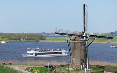 Cruise boat passing by a windmill on a river at Keukenhof, Netherlands.