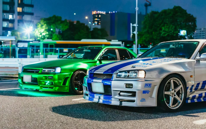 Two modified cars parked in Tokyo at night for the Fast & Furious Tokyo Drift III Experience.