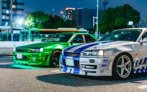 Two modified cars parked in Tokyo at night for the Fast & Furious Tokyo Drift III Experience.