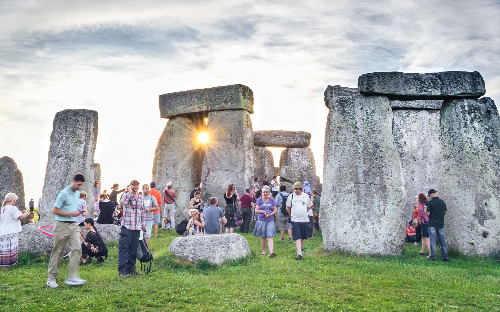 Tourists exploring the inner circle of Stonehenge at sunset.