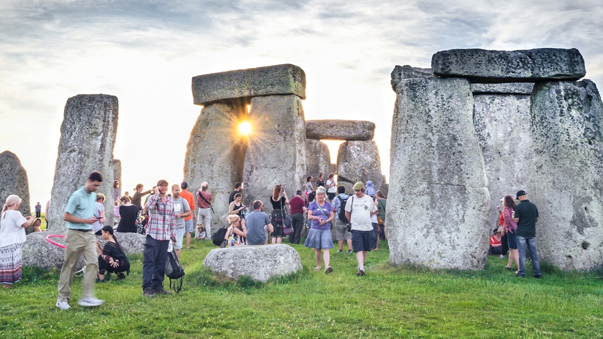Tourists exploring the inner circle of Stonehenge at sunset.