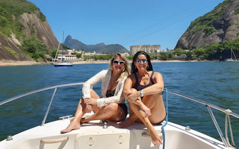 Tourists enjoying a cruise boat ride with Sugarloaf Mountain in Rio de Janeiro.