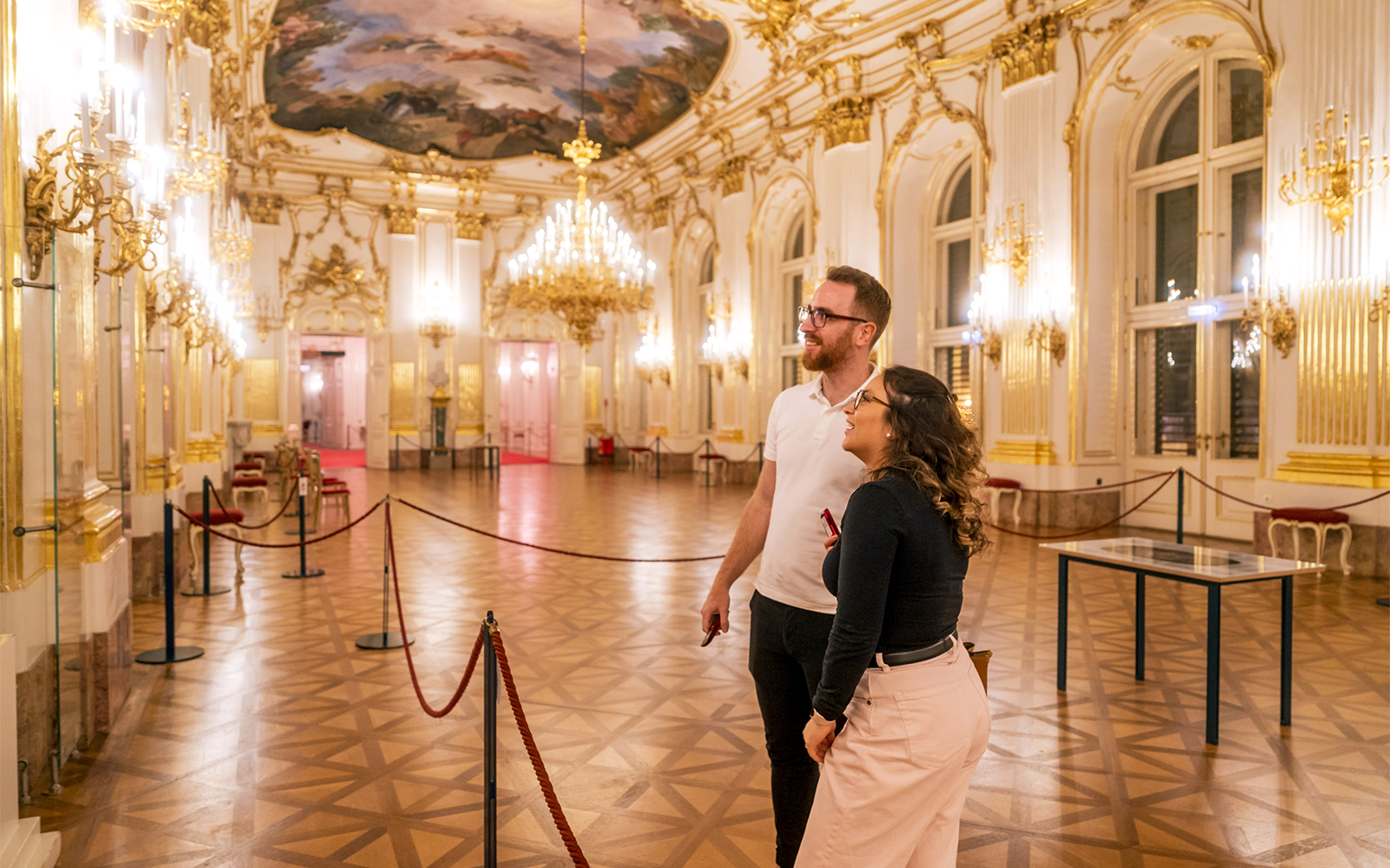 Visitors admiring the ornate interior of Schonbrunn Palace during a tour.