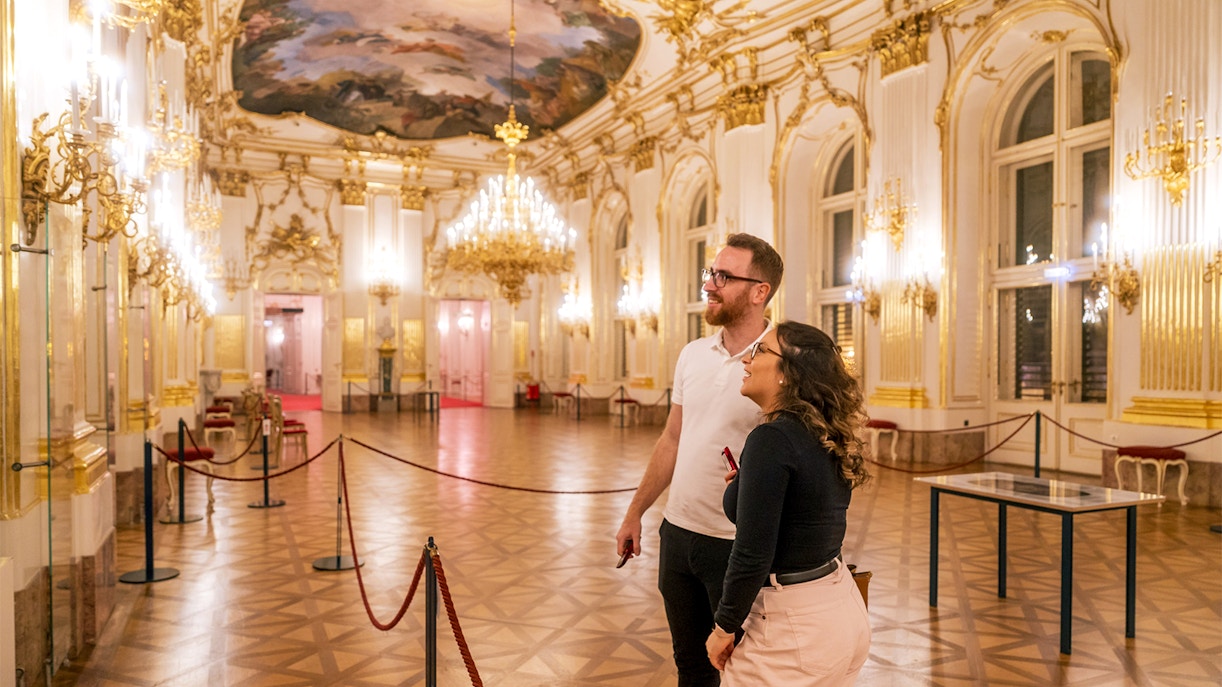 Visitors admiring the ornate interior of Schonbrunn Palace during a tour.