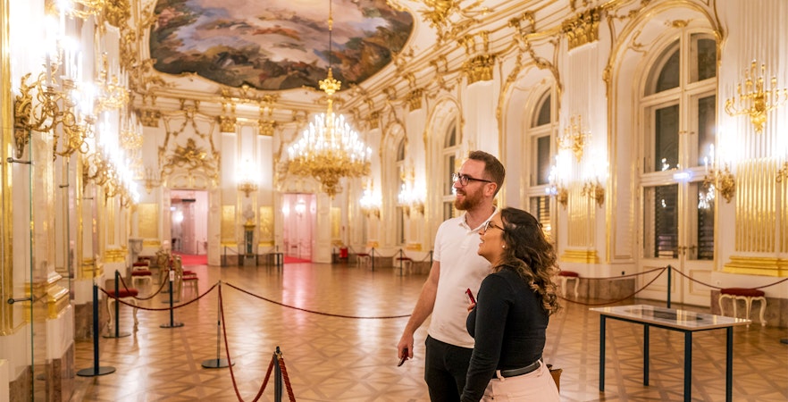 Visitors admiring the ornate interior of Schonbrunn Palace during a tour.
