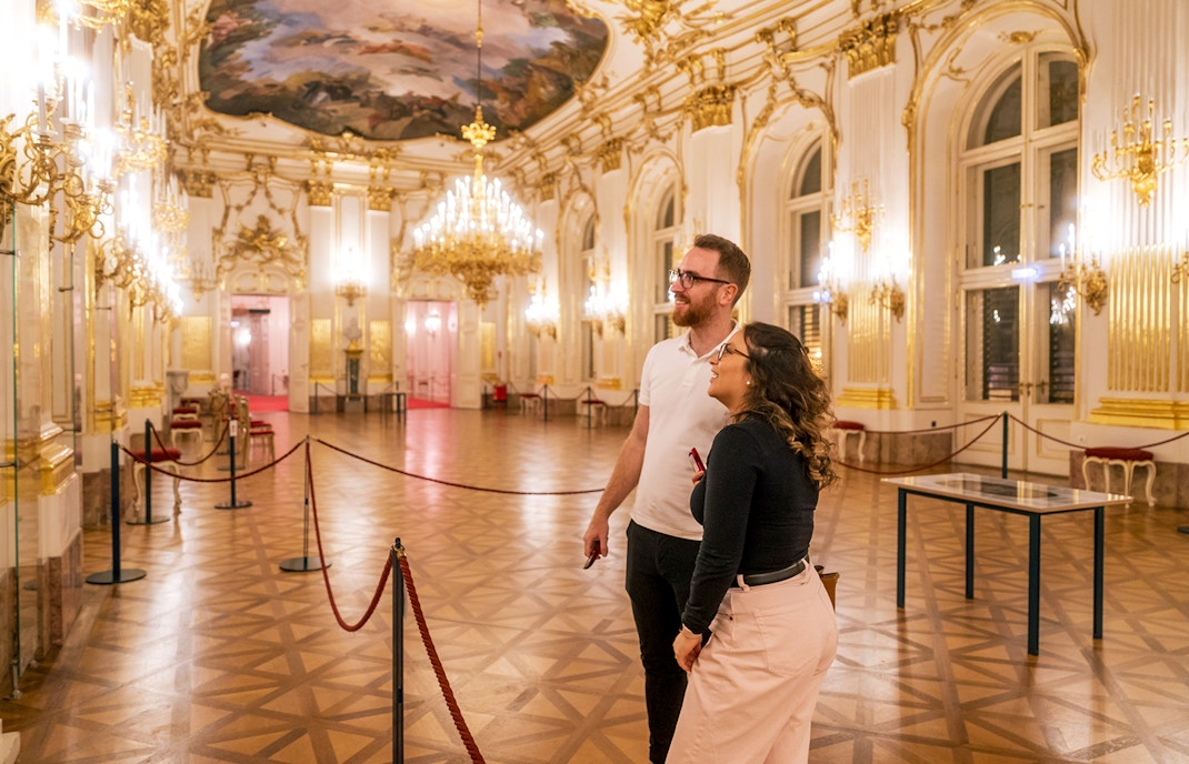 Visitors admiring the ornate interior of Schonbrunn Palace during a tour.