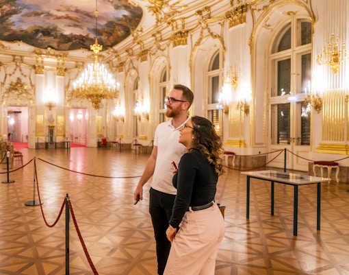 Visitors admiring the ornate interior of Schonbrunn Palace during a tour.