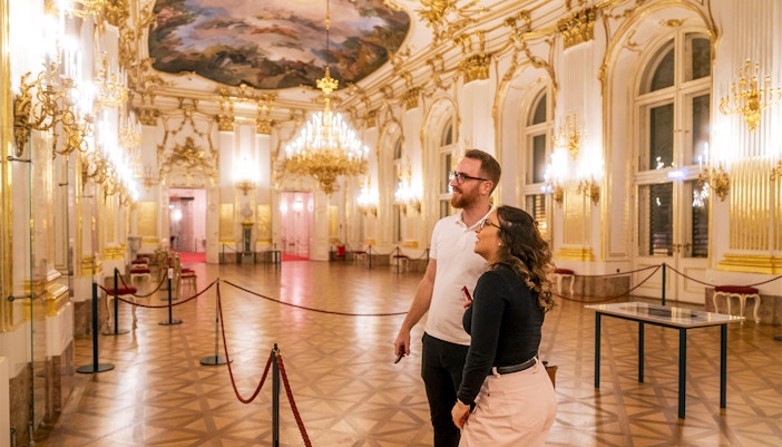 Visitors admiring the ornate interior of Schonbrunn Palace during a tour.
