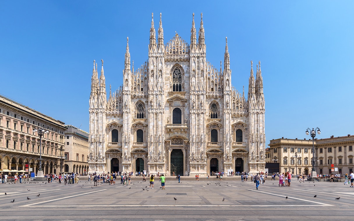 Duomo Milan Cathedral facade with tourists exploring architectural details.