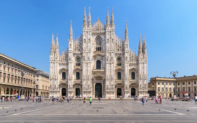 Duomo Milan Cathedral facade with tourists exploring architectural details.
