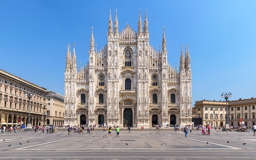 Duomo Milan Cathedral facade with tourists exploring architectural details.