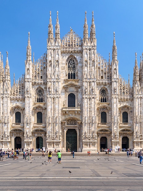 Duomo Milan Cathedral facade with tourists exploring architectural details.
